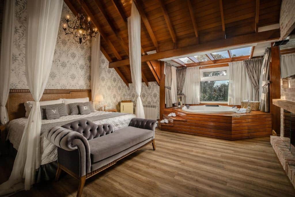 Quarto espaçoso do Hotel Valle Dincanto, com cama de casal e hidromassagem, com janela de vidro ao lado e vista para a natureza