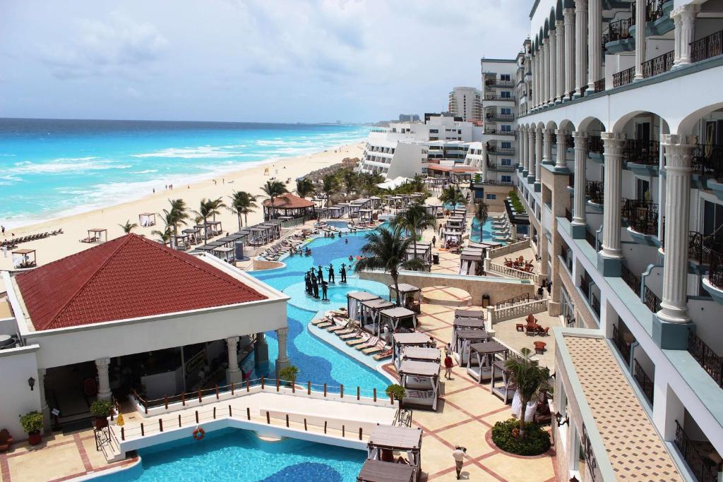 vista da sacada do Hyatt Zilara Cancun para o mar e a praia, além da piscina do hotel. O dia está nublado e não há pessoas descansando na piscina