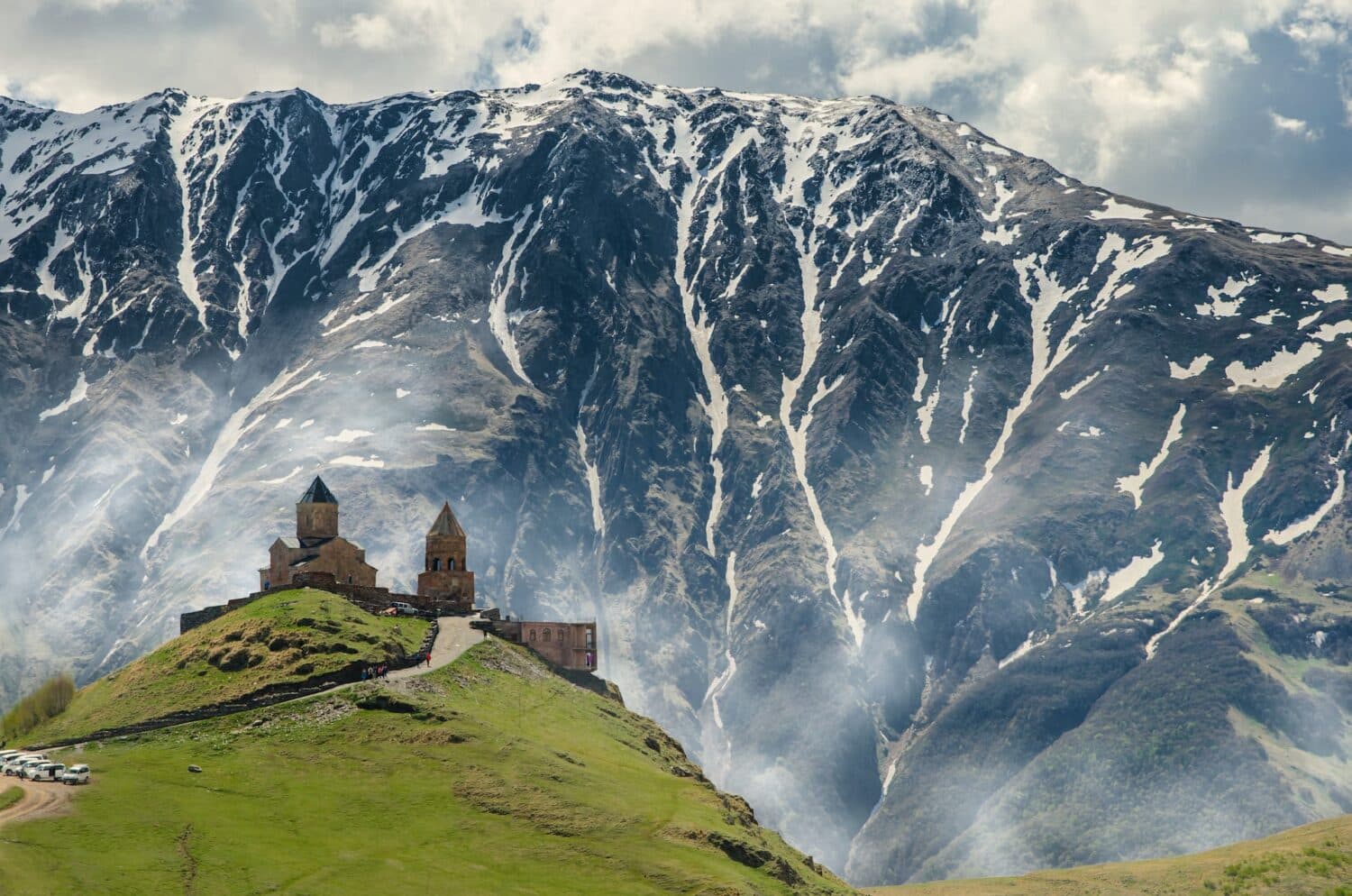 Foto da Igreja da Trindade Gergeti com uma montanha nevada ao fundo - Foto: Iman Gozal via Unsplash