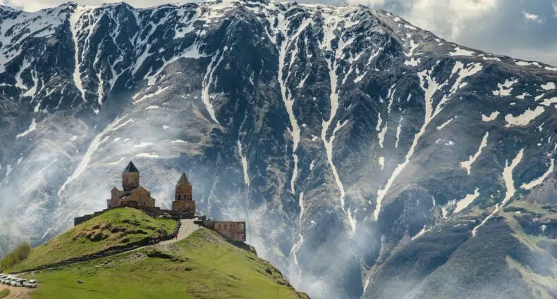 Foto da Igreja da Trindade Gergeti com uma montanha nevada ao fundo - Foto: Iman Gozal via Unsplash