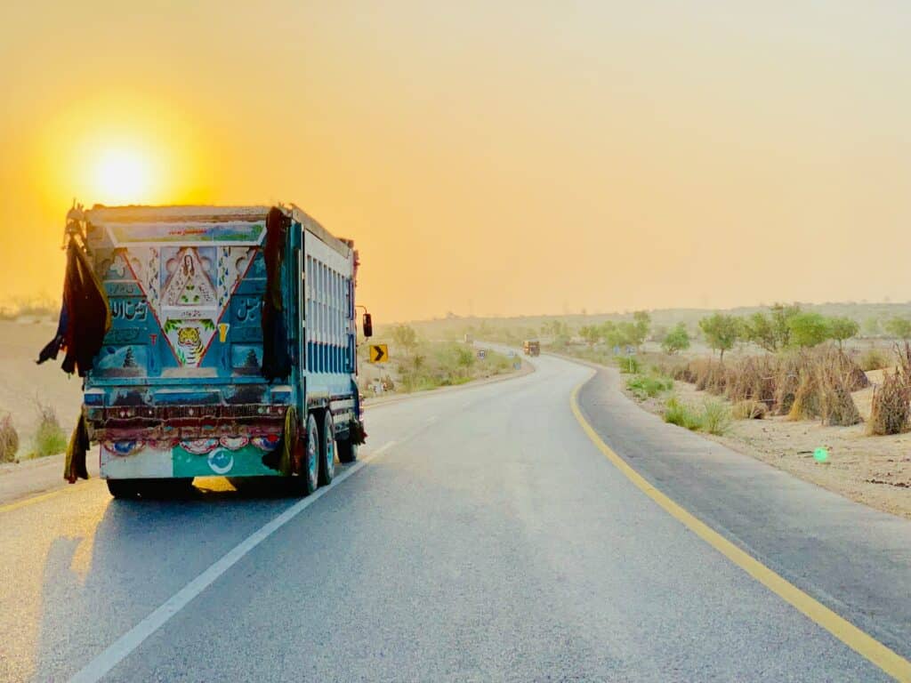 Pôr do sol e caminhão colorido na Islamkot Road, estrada no Paquistão
