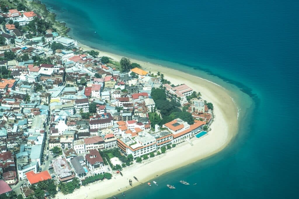 Stone Town em Zanzibar, um bairro com casas e hotéis à beira-mar, o mar é bem escuro e a areia é clara, para representar o seguro viagem Zanzibar