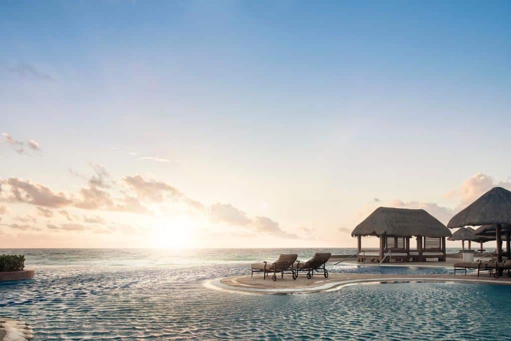 pôr do sol na piscina do JW Marriott Cancun Resort & Spa com vista para o oceano e duas espreguiçadeiras