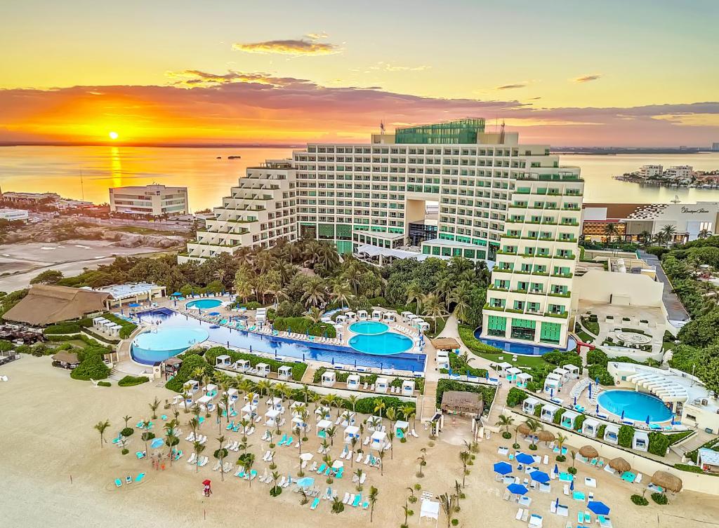 pôr do sol no oceano ao fundo do Live Aqua Beach Resort Cancun em frente, mostrando toda a estrtura do prédio e das piscinas