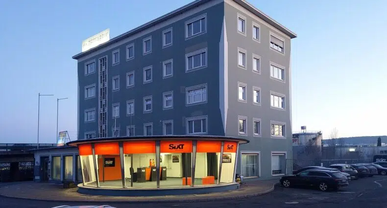 Loja Sixt na cidade alemã de Bayreuth, no andar térreo de um rpédio de quatro andares, com paredes cinza e janelas quadradinhas