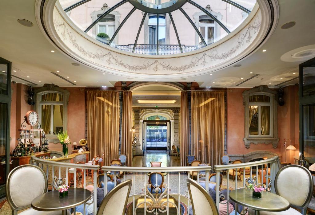 lounge compartilhado com várias poltronas em decoração clássica e uma abóbada de vidro em cima no Château Monfort - Relais & Châteaux um dos hotéis em Madri