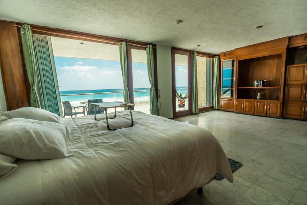 quarto do Luxury Beachfront Villa com varanda privativa e vista para a praia, mostrando a cama de casal à esquerda e um grande móvel de madeira à direita