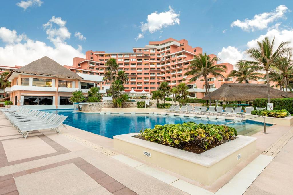 vista da piscina e da fachada do Omni Hotel & Villas com várias espreguiçadeiras e um céu azul ao fundo
