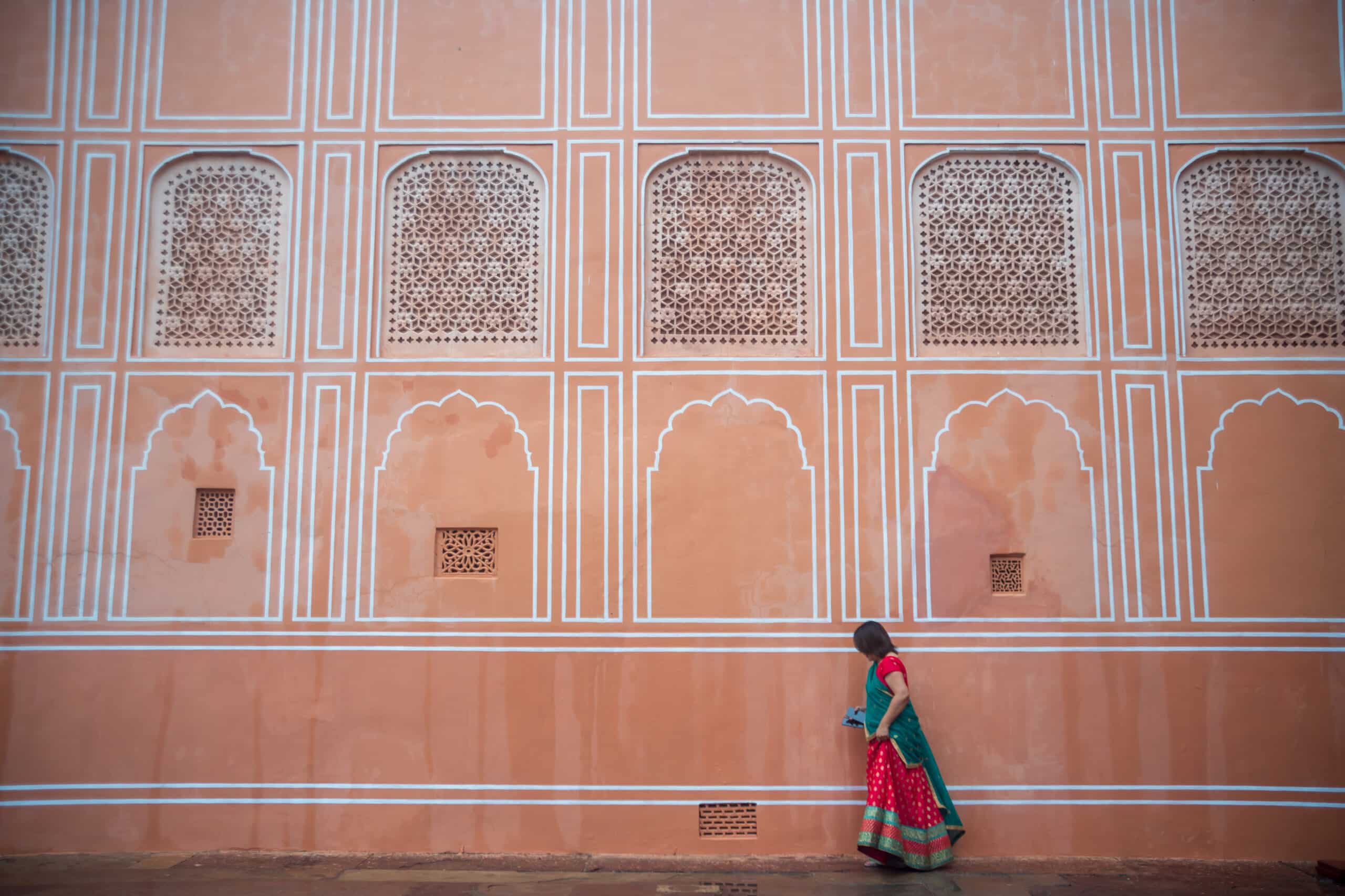 Mulher indiana andando em frente a uma parede cor de rosa para ilustrar seguro viagem Jaipur. - Foto: Pijarn Jangsawang via Pxhere