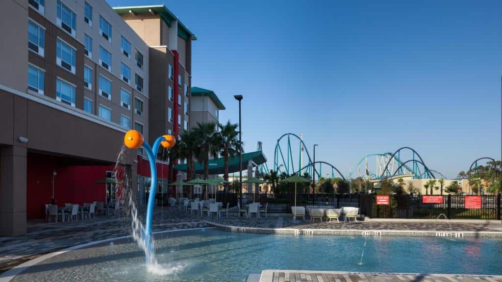 piscina com prédio ao lado e mais ao fundo a vista de uma montanha-russa no Holiday Inn Express & Suites - Orlando At Seaworld, an IHG Hotel, um dos hotéis em Orlando