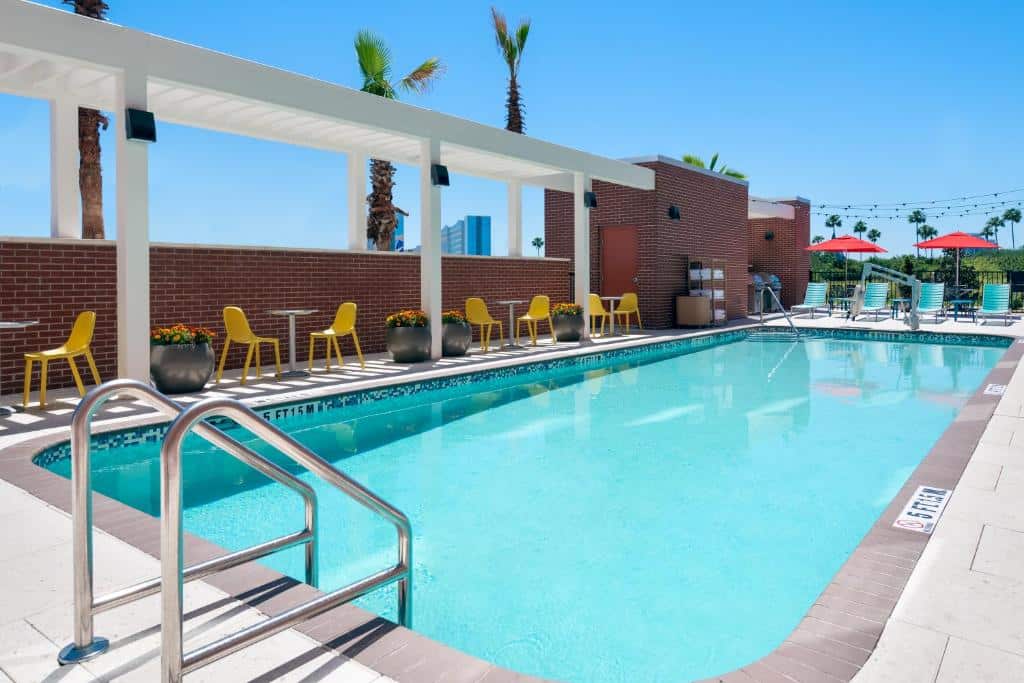 piscina retangular com escadinha e e cadeiras ao redor no Home2 Suites By Hilton Orlando Near Universal um dos hotéis em Orlando