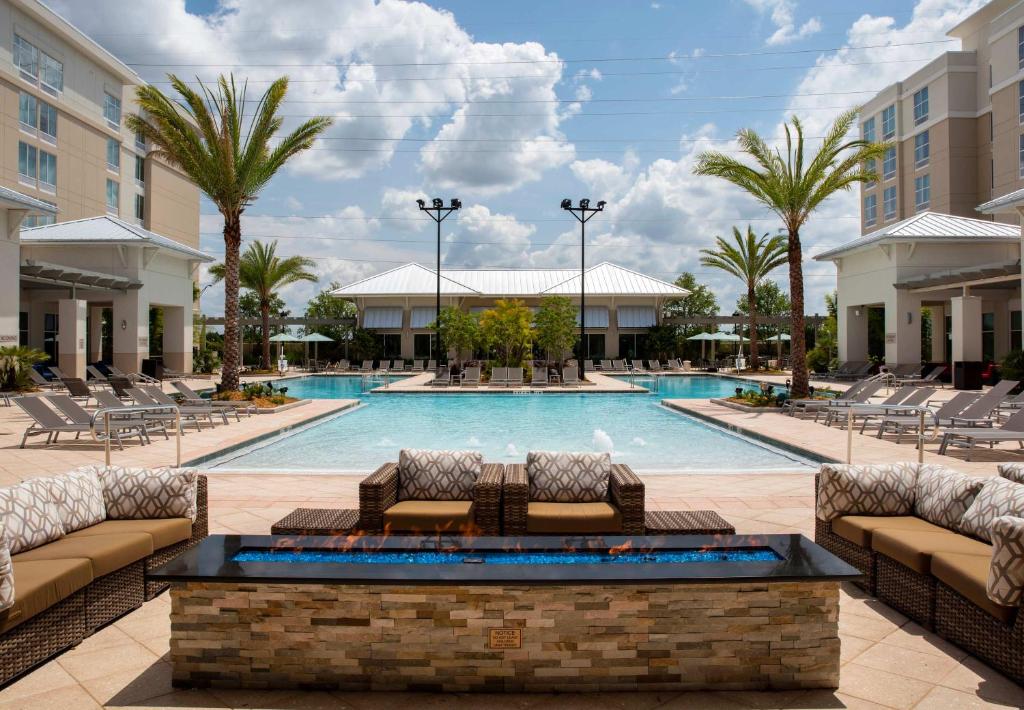 vista da piscina de frente, com sofás e poltronas ao redor e os prédios do SpringHill Suites by Marriott Orlando at FLAMINGO CROSSINGS Town Center-Western Entrance dos lados, um dos hotéis em Orlando