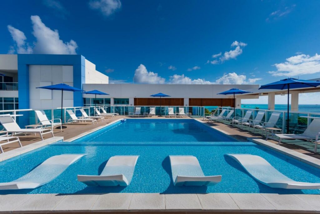 Piscina ampla no Aquamare Hotel com diversas espreguiçadeiras dentro e fora da piscina