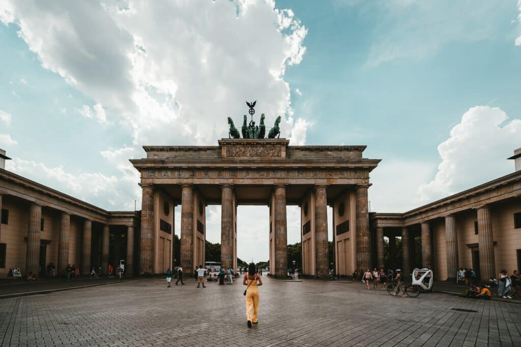 Mulher de amarelo, de costas, andando em direção ao Portão de Brandemburgo, em Berlim