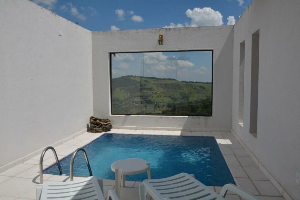 Piscina privativa da Pousada Villa dos Leais com uma ampla janela na frente para ver as montanhas