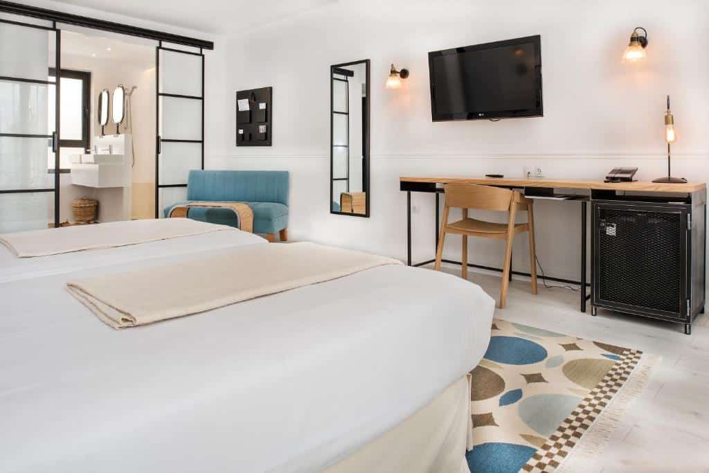 quarto do 7 Islas Hotel com cama e banheiro grande, tv e balcão com cadeira
