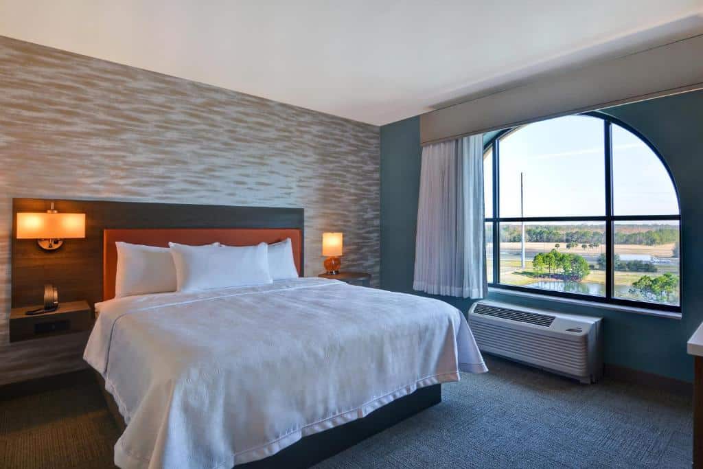quarto com cama de casal e janela com vista da grama no Home2 Suites By Hilton Orlando Flamingo Crossings, FL, um dos hotéis em Orlando