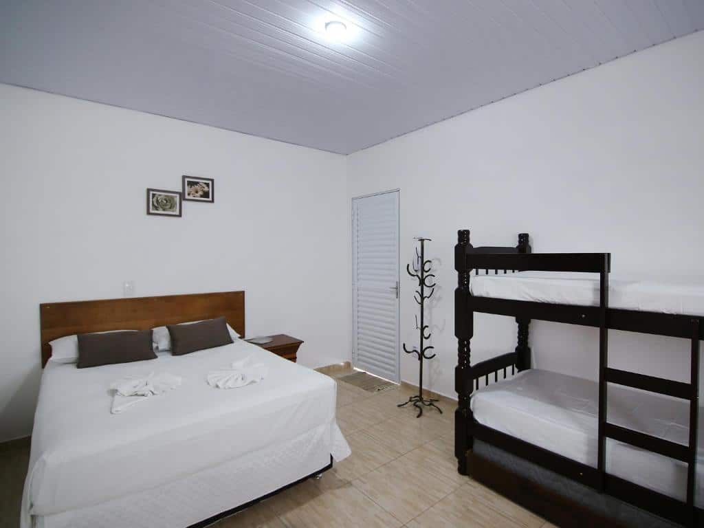 Quarto na Pousada Vale da Montanha com uma cama de casal e uma beliche, ambiente simples e novo, para representar pousadas em Serra Negra