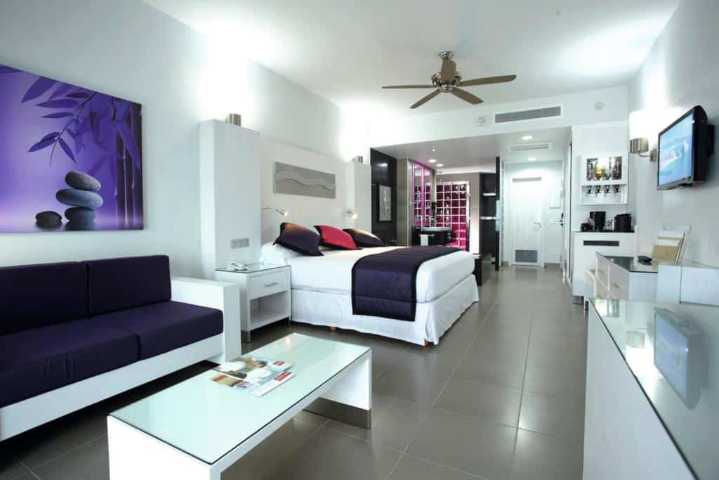 suíte do Riu Palace Peninsula com uma cama de casal, uma sala de estar e um banheiro privativo