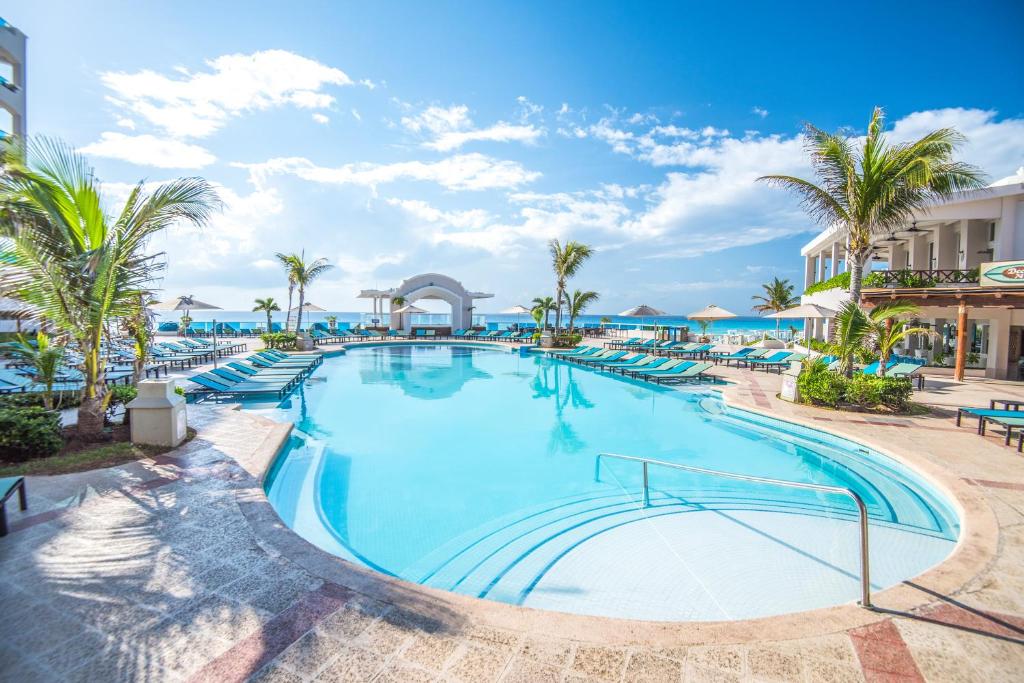 piscina do Wyndham Alltra Cancun resort com várias espreguiçadeiras ao redor e uma vista ampla do mar