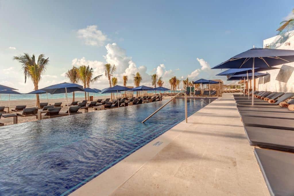piscina em frente a praia com espreguiçadeiras vazias no Royalton CHIC Cancun