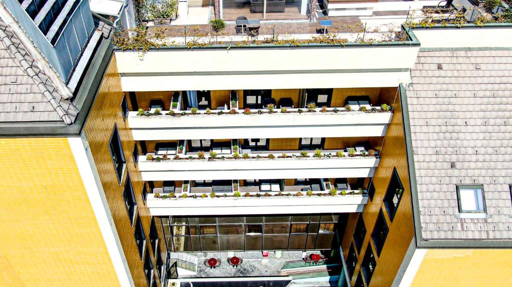 vista de frente das sacadas dos apartamentos e do terraço com florzinhas e cadeiras no Art Hotel Navigli, um dos hotéis em Milão
