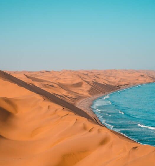 Sandwich Harbour, deserto na Namíbia, com dunas amareladas e parte de um lado azulado