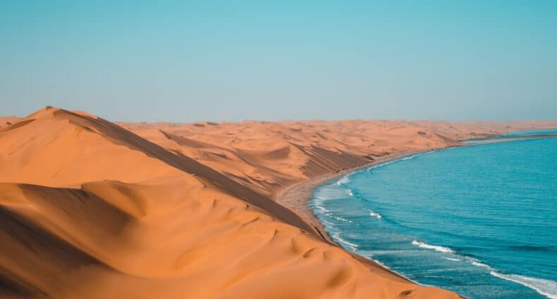 Sandwich Harbour, deserto na Namíbia, com dunas amareladas e parte de um lado azulado