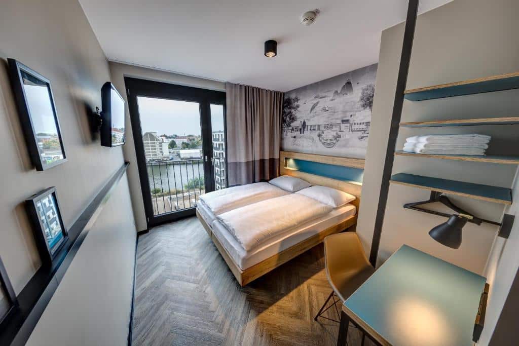 Quarto do Schulz Hotel Berlin, com duas camas de solteiro, TV e porta da varanda de vidro com vista do rio