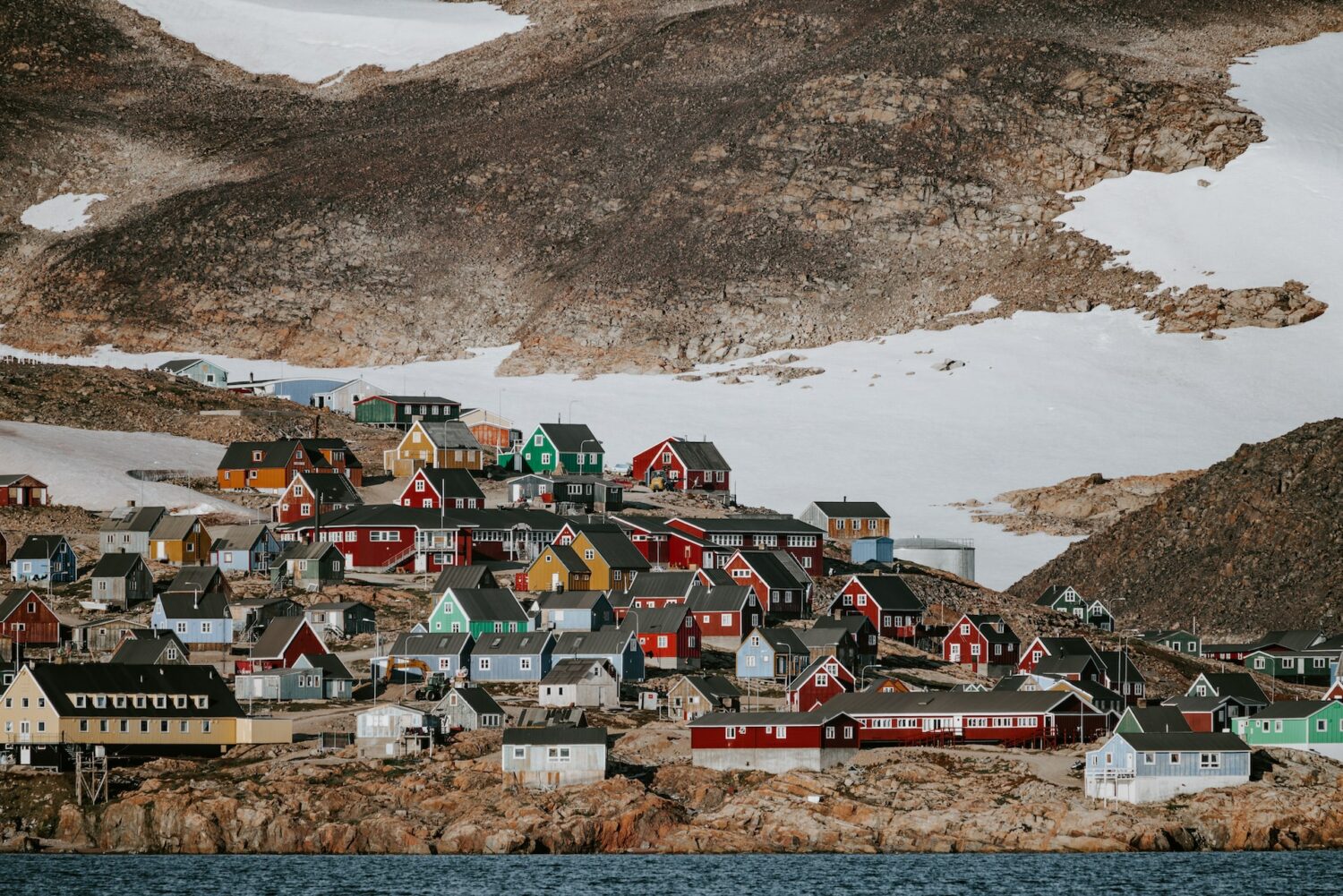 scoresby sund na groenlândia com casas coloridas entre neve e montanhas durante o dia ilustrando post seguro viagem groenlândia