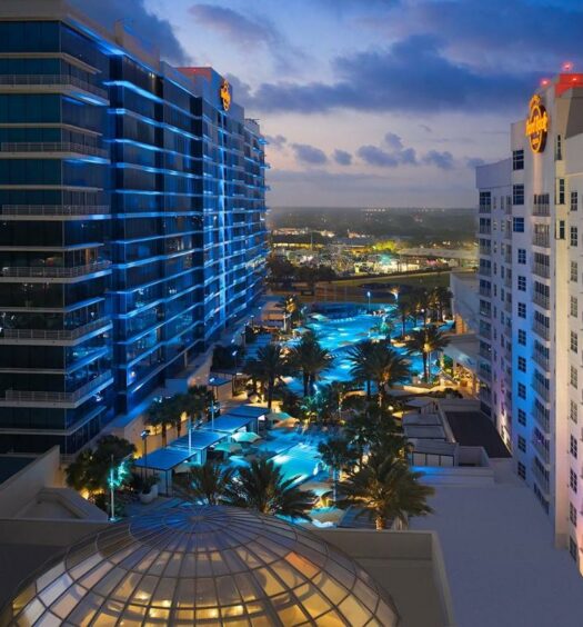 Vista aérea do Seminole Hard Rock Hotel and Casino Tampa com tudo iluminado de noite, com vista para as piscinas no entardecer