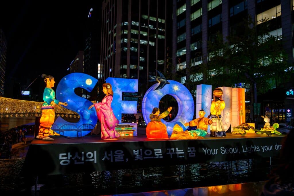 Letreiro iluminado da cidade de Seul na Coréia do Sul, cercado por grandes construções para representar o seguro viagem Seul.