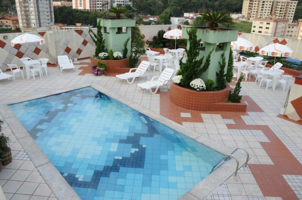 Piscina do Serra Negra Paladium Hotel com um deck amplo na cobertura da propriedade com mesas e cadeiras