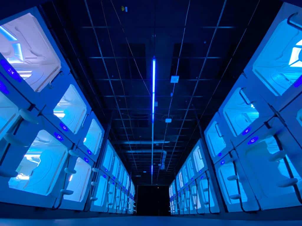 Corredor com acomodações iluminadas com led azul do Space Night Capsule Hostel, em Berlim