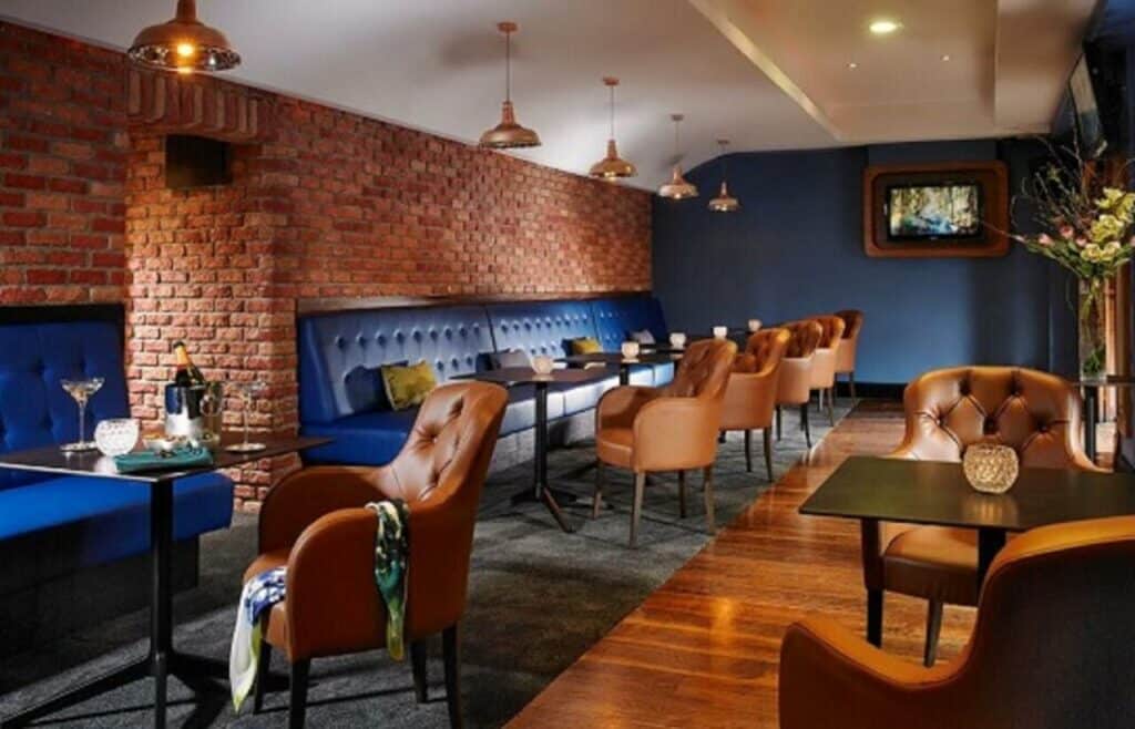 Local para refeições no Temple Bar Hotel que parece com pub antiga, com bancos estofados em azul, poltronas cor de caramelo e chão de madeira