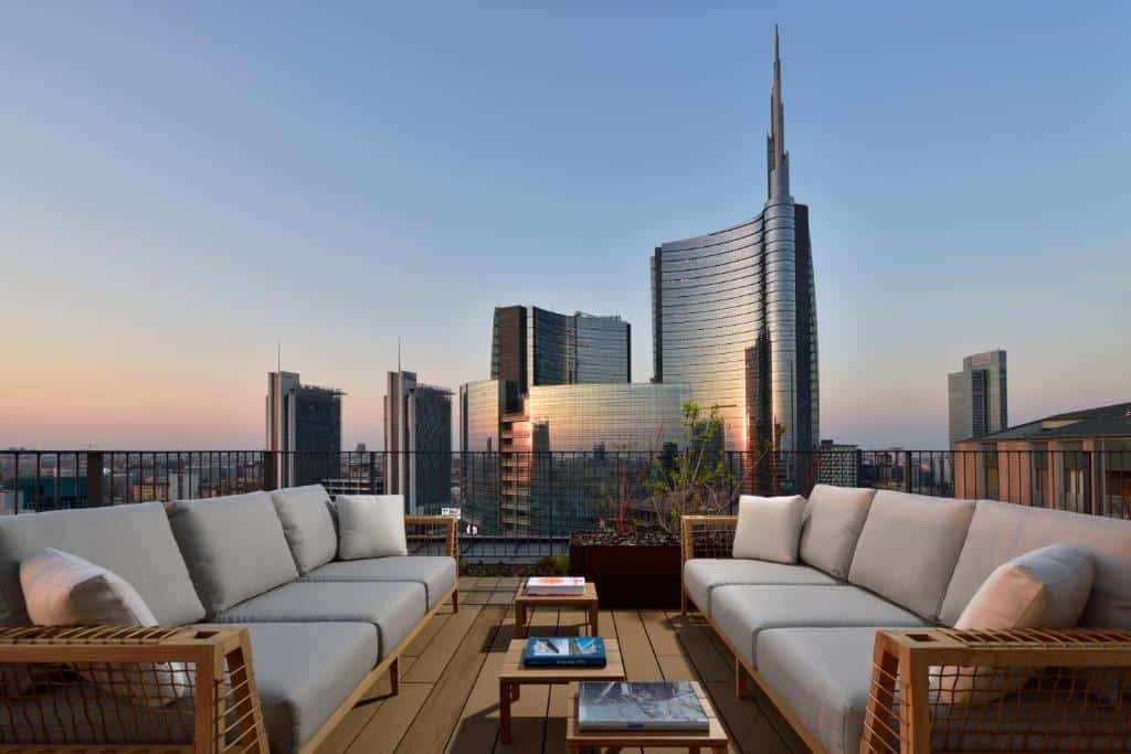 terraço com dois sofás compridos cara a cara com mesinha de centro e vista dos prédios ao entardecer no Milano Verticale | UNA Esperienze um dos hotéis em Milão