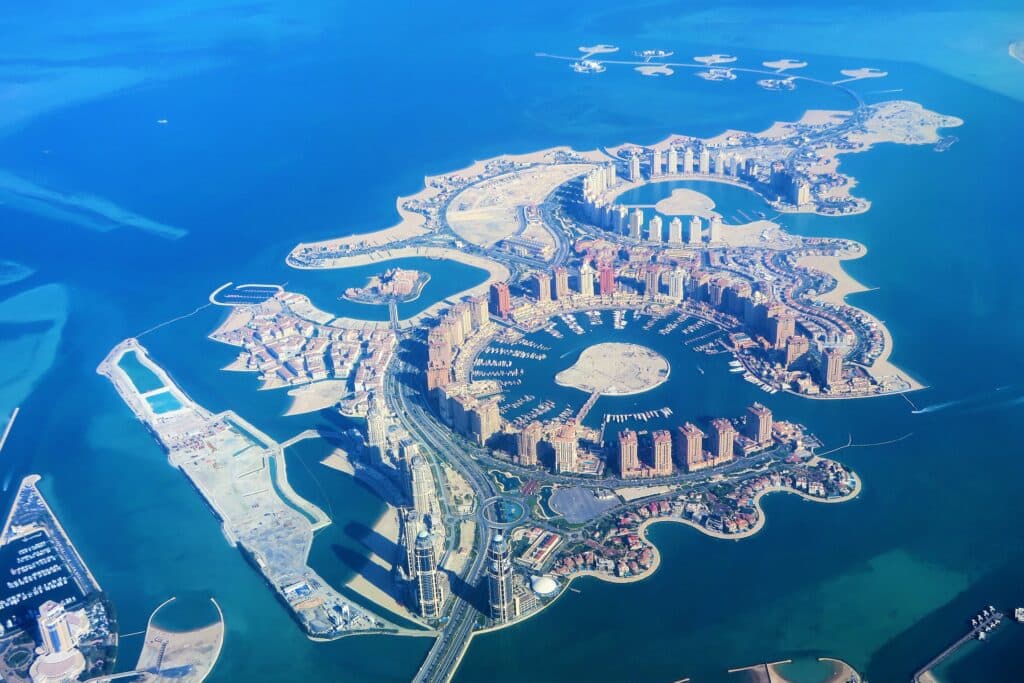 Visão aérea de uma ilha artificial com prédios e construções e cercada de água turquesapara ilustrar o post seguro viagem Doha. - Foto: Konevi via Pixabay