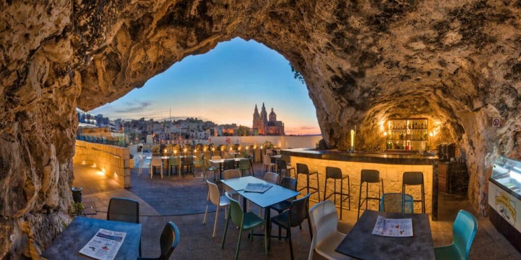 Área do restaurante em um terraço ao ar livre em Pergola Hotel & Spa com algumas rochas formando o bar, para representar hotéis em Malta