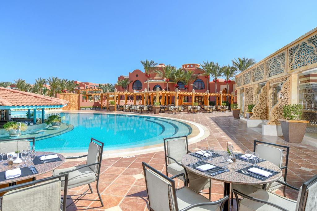 vista da piscina do Magic World Sharm - Club by Jaz em Sharm el Sheikh com mesinhas e cadeiras, além da estrutura em estilo clássico árabe