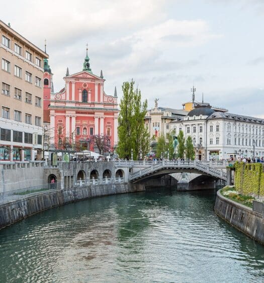 vista do rio na capital Liubliana com construções barrocas em tons de laranja e vermelho e branco com uma ponte acima do rio, que ilustra o post de chip celular Eslovênia