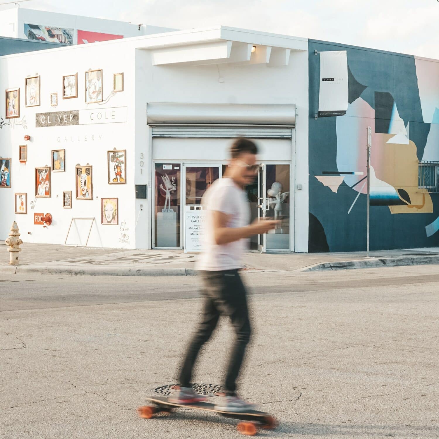 pessoa andando de skate enquanto mexe no celular com paredes grafitadas e coloridas de fundo em Wynwood que pode ser fotografado com o chip celular Miami