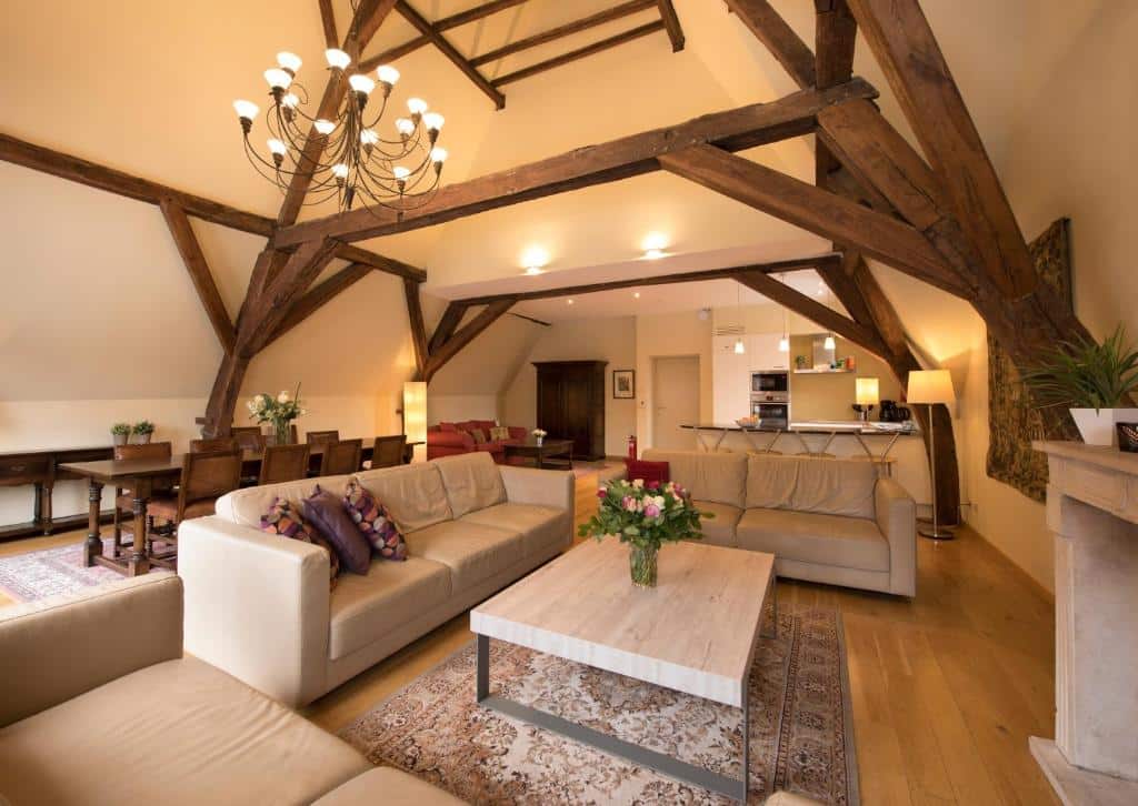 apartamento com dois sofás e mesinha de centro, tv e mesa com cadeiras com estrutura de madeira e lustre no De Drie Koningen em Bruges