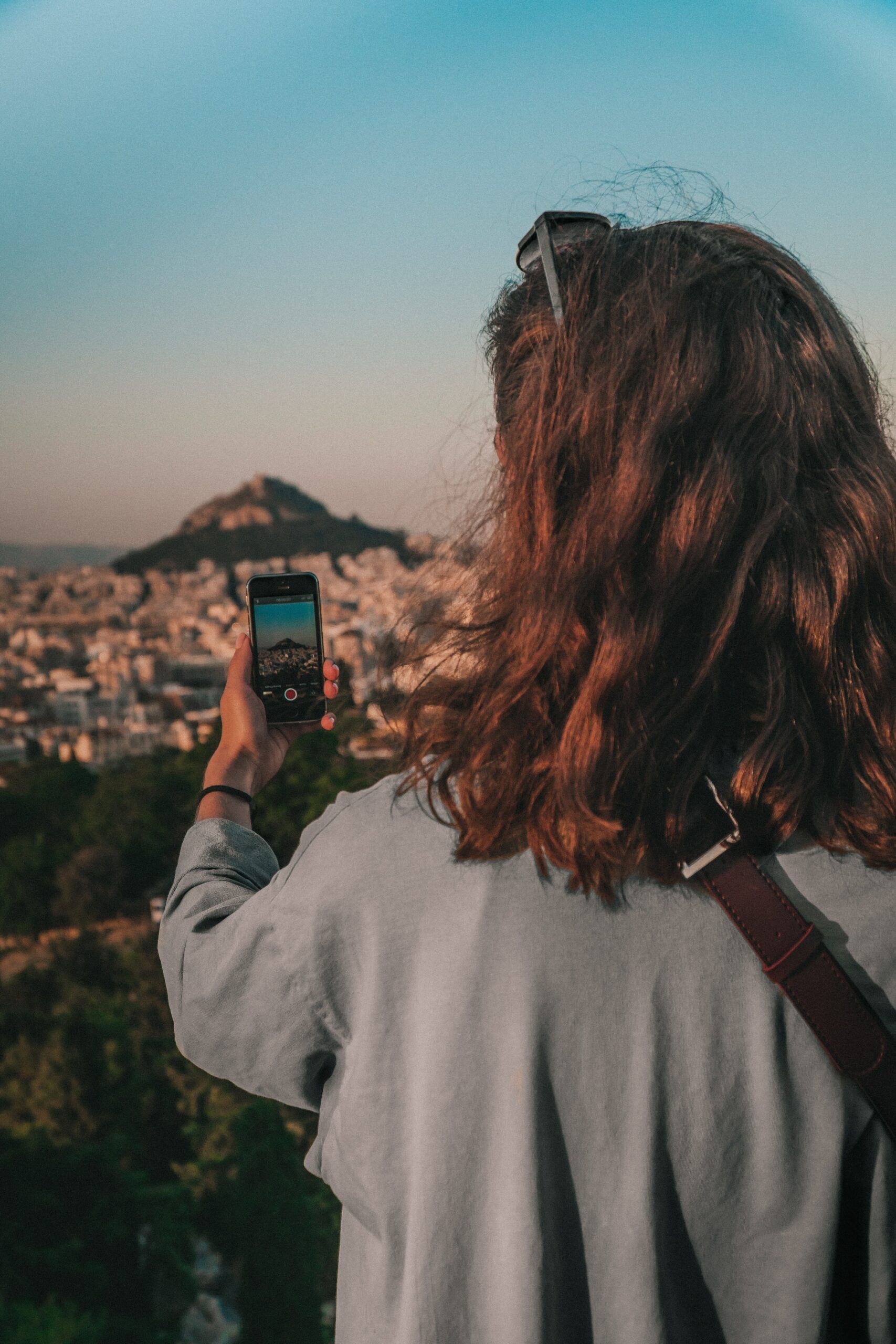 Mulher com celular na mão para tirar foto da cidade em Atenas- Representa chip celular Atenas