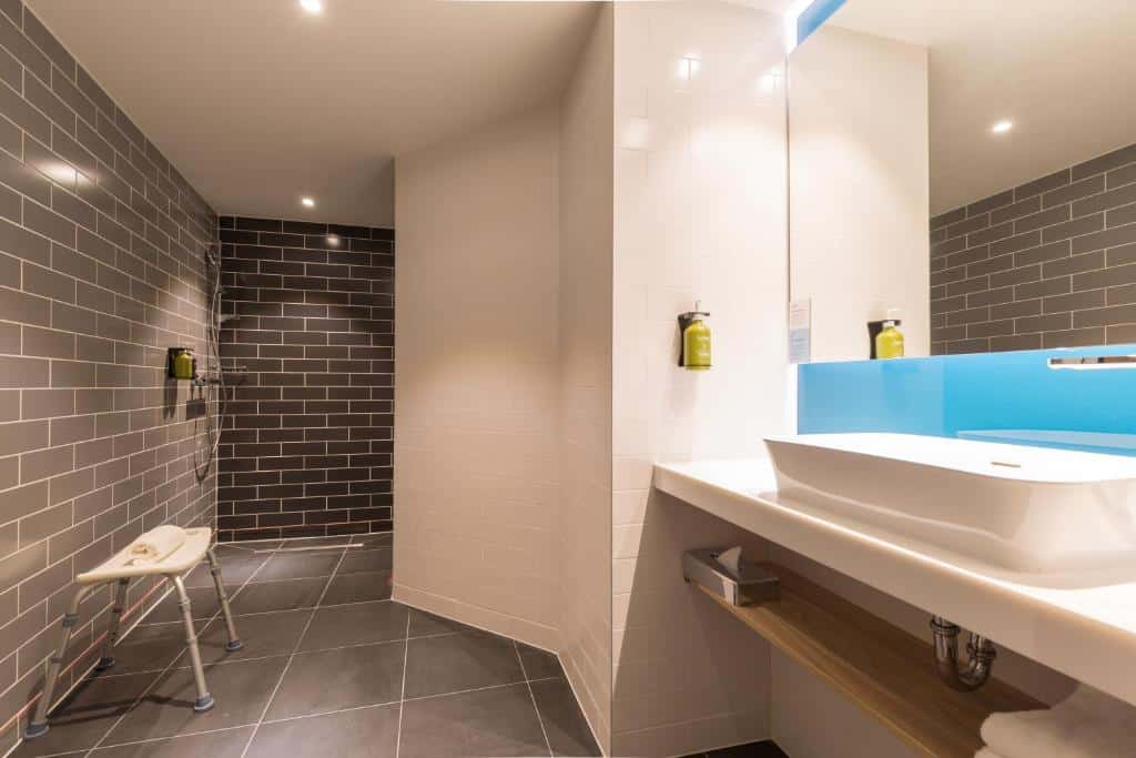 banheiro adaptado do quarto Holiday Inn Express Brussels-Grand-Place com ambientes amplos e cadeira de apoio para banho