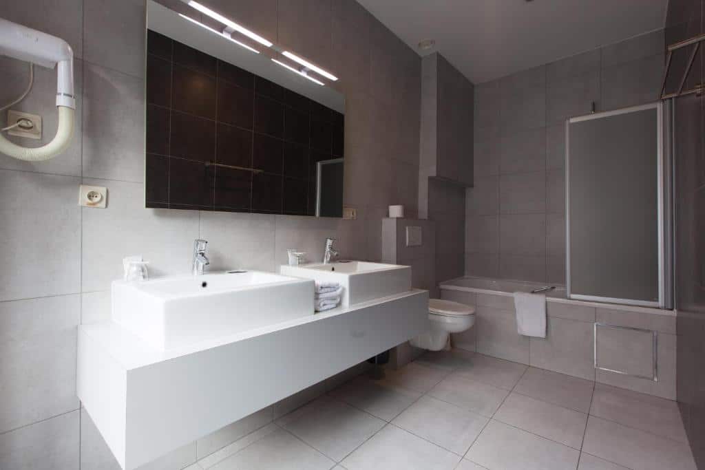 banheiro amplo com detalhes em mármore do Hotel Boterhuis com duas pias, espelho grande e espaço de banheira