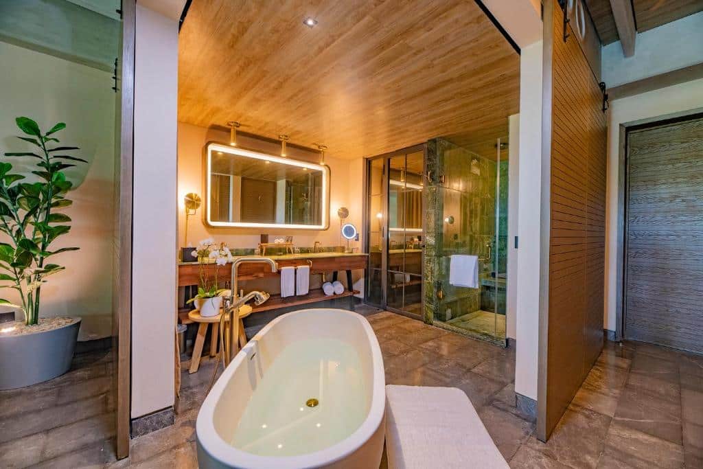 banheiro do Atelier Playa Mujeres-All Inclusive com uma banheira, um boxe e um grande espelho iluminado ao fundo