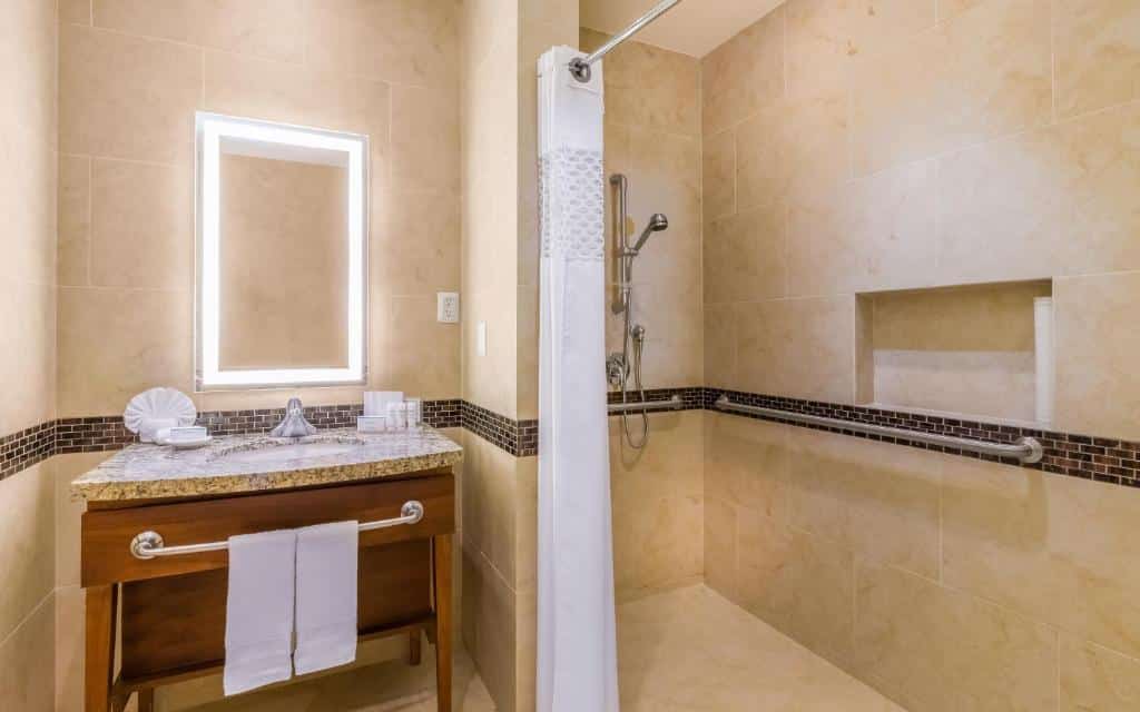 Banheiro do Hampton Inn & Suites by Hilton Los Cabos adaptados com barra de segurança no chuveiro, pia baixa com barra de segurança.