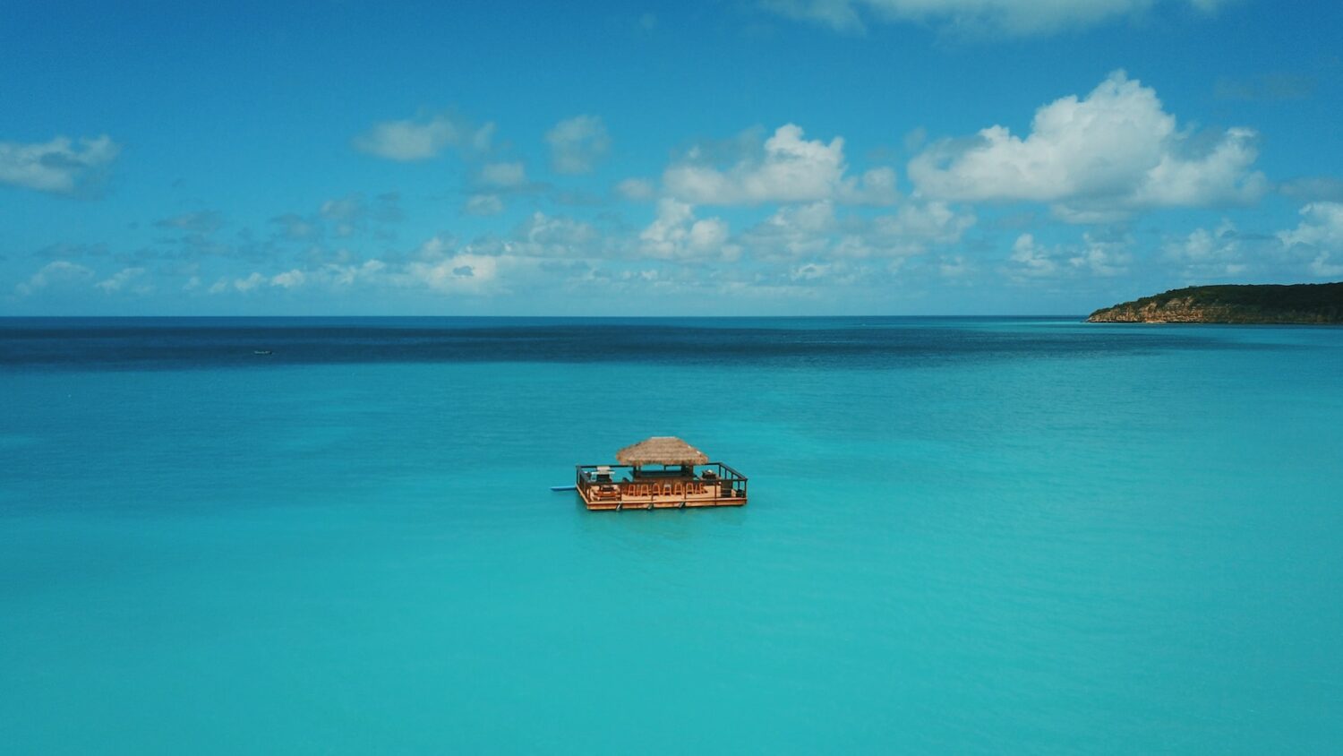 Um mar muito azul e uma casinha no meio do mar