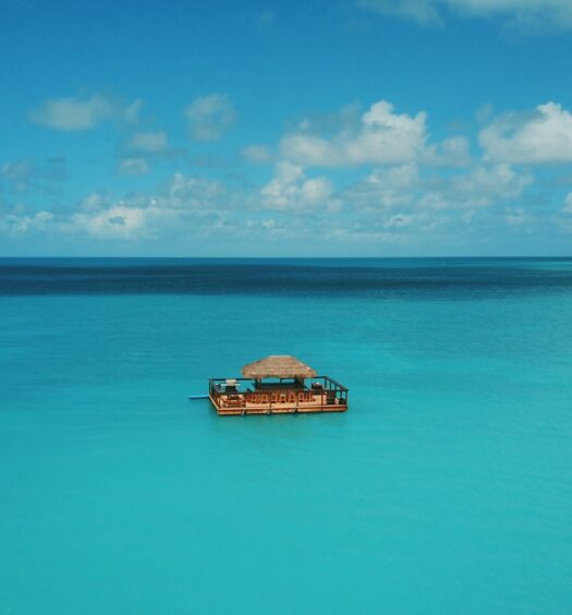 Um mar muito azul e uma casinha no meio do mar