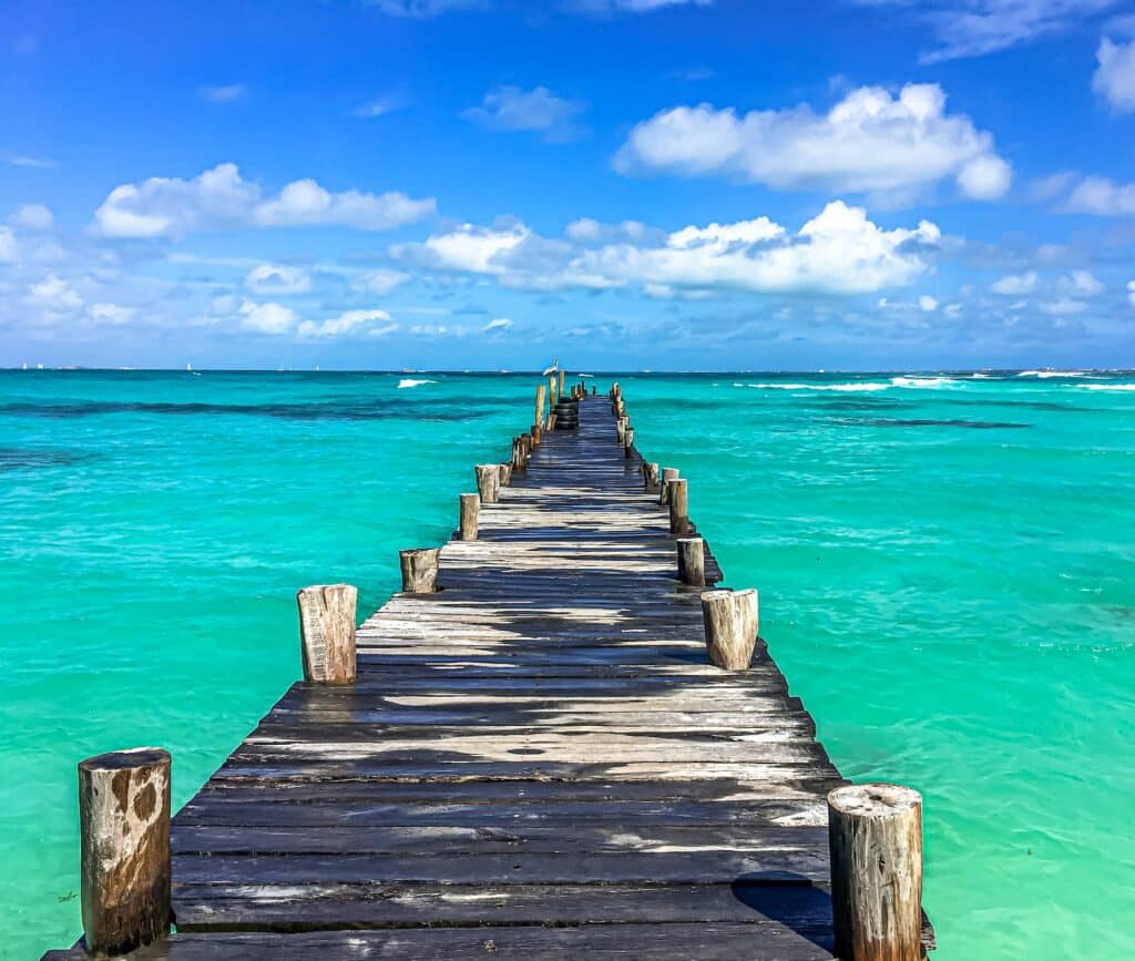 doca de madeira que avança em direção ao mar verde cristalino em uma praia de Punta Cancun, que ilustra o post de chip celular Cancun